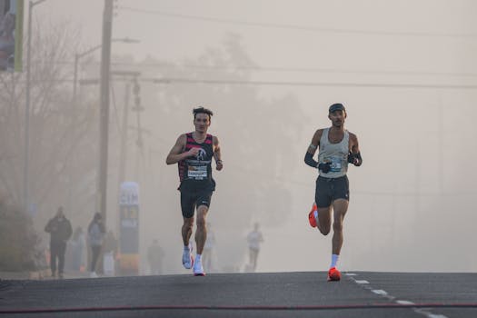 Two marathon runners lead the race on a foggy morning, showcasing athletic endurance.
